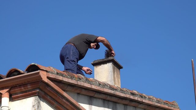 The man on the roof cleaning chimney grill avec part of the brush for cleaning the fireplace chimney
