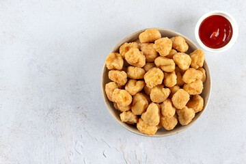 Chicken popcorn in a bowl with ketchup on a white background. Top view. Copy space. Fast food.