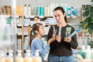 Woman with a daughter buys toothbrushes with high-quality bristles in a pharmacy