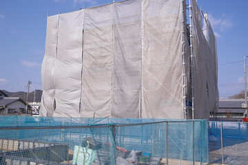 養生シートに覆われた建築中の住宅