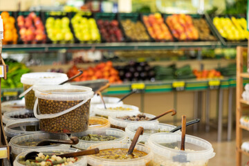 Plastic buckets are filled with pickled olives in brine. Wide range of vegetable store, fresh and processed vegetables and fruits.