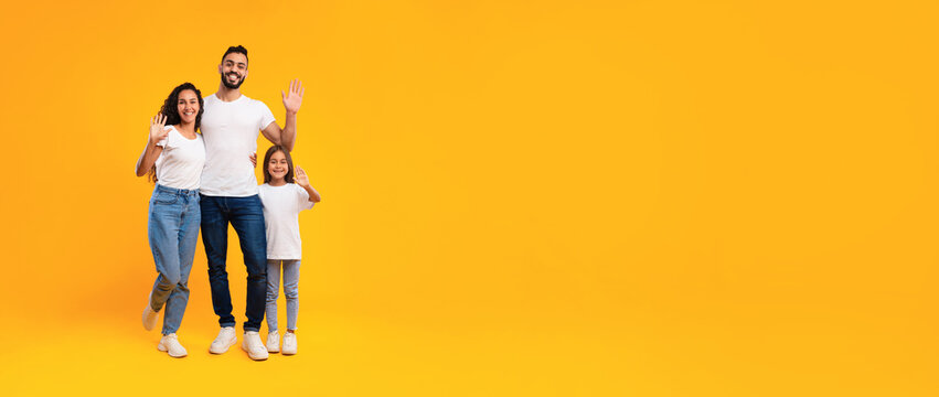 A joyful family enjoys a sunny moment together. The father, mother, and daughter pose happily on a vibrant yellow background, all wearing casual outfits, creating a warm and inviting scene. - Powered by Adobe