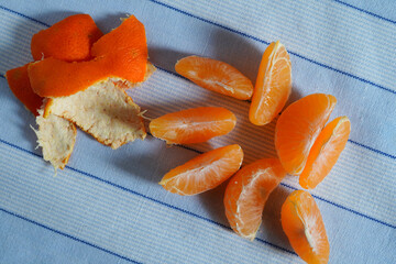 Closeup of detached clementine segments and peel pieces on blue cloth