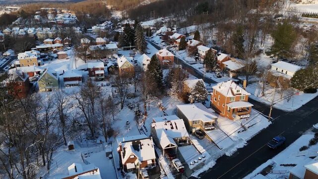 Wide forward-moving aerial establishing shot of a typical Western Pennsylvania residential neighborhood at winter dusk with snow covered homes and streets. Pittsburgh suburbs. 14983  