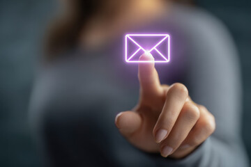 Person interacting with glowing envelope icon on touchscreen interface symbolizing digital communication and email messaging in a modern technology concept