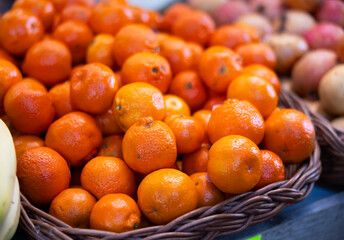 Ripe, freshly picked tangerines in a box at a farmer market. Abundant supermarket window with citrus fruits close up