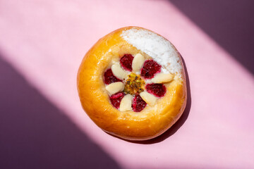 one raspberry and white chocolate pastry on a plain background with shadows on either side