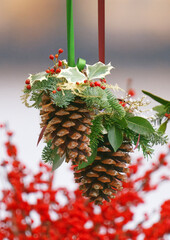 Natural Christmas decorations made of pine cones, evergreen branches and berries hanging at florist stall during advent season at Naplavka farmers market in Prague, Czech Republic.