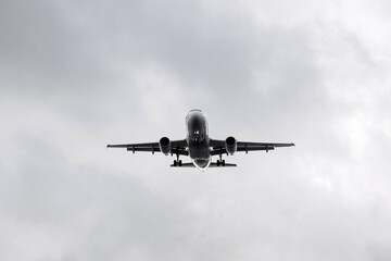 Airplane flying through cloudy sky, showcasing its underbelly and landing gear, capturing the essence of air travel and aviation technology in motion