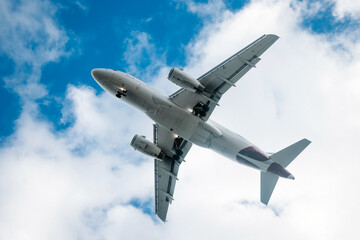 Commercial airplane flying high above the clouds against a bright blue sky, showcasing aviation technology and the beauty of air travel in a dynamic aerial perspective