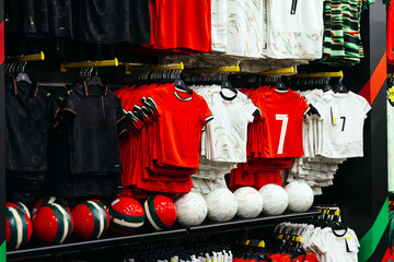 Colorful display of sports jerseys and soccer balls arranged neatly on shelves, showcasing vibrant designs and patterns in a retail environment for athletic apparel
