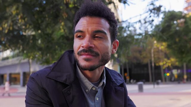Portrait of young handsome bearded businessman standing outdoors in a city square, relaxing and looking around with a calm and thoughtful expression during a pleasant afternoon - Powered by Adobe
