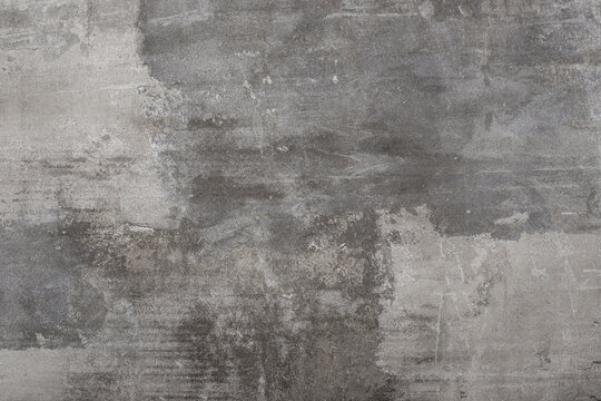 Dark gray concrete texture with noticeable rough areas and uneven, aged surfaces, grunge or industrial background.