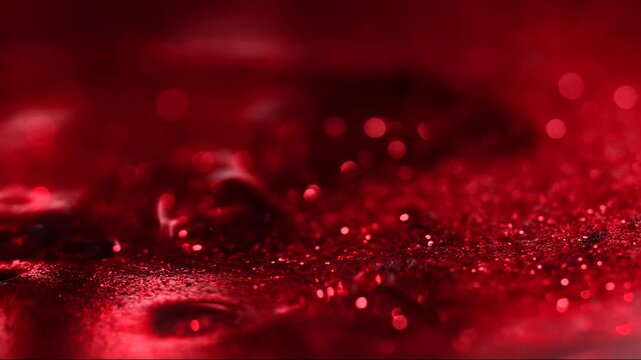 Abstract red macro background with shimmering glitter particles and soft bokeh lights.