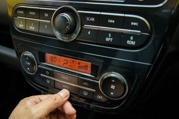 A close-up shot of a hand operating the climate control and radio system in a modern car dashboard, showing the 'AUTO' button engaged and the temperature set to $18.0^{\circ}\text{C}$.