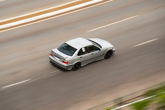 Silver BMW 3 Series E36 sedan driving fast, Classic German youngtimer car panning shot