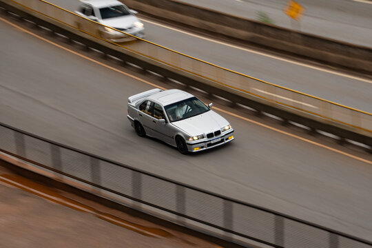 Silver BMW 3 Series E36 front view driving, Classic German sedan high angle panning