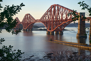 Obraz premium A scenic view of the iconic red cantilever Forth Bridge near South Queensferry, spanning the Firth of Forth in Scotland.