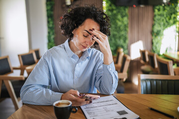 Stressed woman feeling headache working in cafe