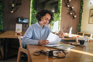 Woman reviewing paperwork work documents inside a cafe