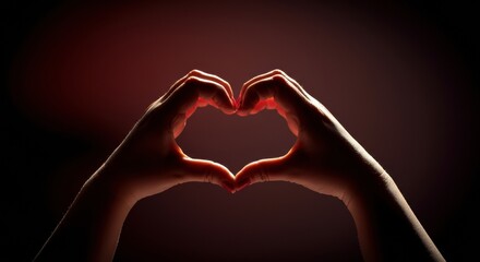 Fototapeta premium Hands forming heart shape with dramatic backlighting and soft red gradient