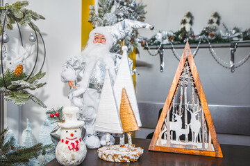  Festive Christmas display features white Santa, stylized fabric trees, and a cheerful snowman with red accents. Wooden reindeer decor and lush garlands complete the cozy, holiday-themed arrangement