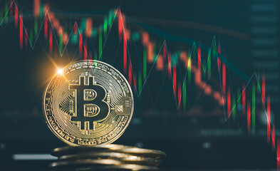 A shiny gold Bitcoin coin stacked on other coins, set against a dark background with red and green candlestick charts illustrating a volatile cryptocurrency market downtrend.