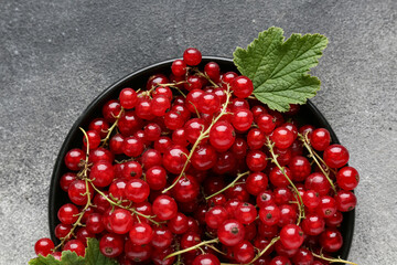 Plate with fresh red currants on grunge background