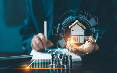 A person writing notes next to a calculator, with a miniature house and a line graph showing the rising value and potential for real estate investment and growth.