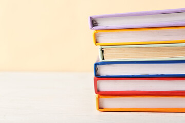 Stack of colorful books on white wooden table against beige background