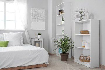 Interior of modern stylish comfortable bedroom with shelving units and different houseplants