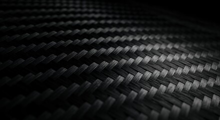 A detailed macro view of a dark gray carbon fiber weave displaying a diagonal pattern, highlighting its intricate texture and modern material strength.