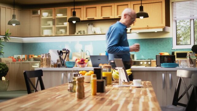Senior adult in a calm kitchen setting scrolling apps on her laptop, enjoying peaceful retired life. Woman showing a gentle smile, simple moments that reflect relaxed domestic living. Camera A.