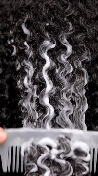 Application of Hair Mousse with Comb on Black Curly Hair Textured Background Demonstrating Product Application for Advertisement and Promotion