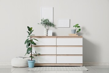Interior of living room with chest of drawers, pouf and houseplants