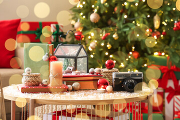 Books with Christmas balls, candles and photo camera on table in living room