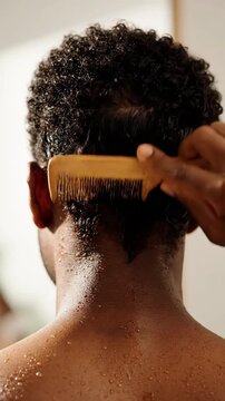 Close-Up of Back View of a Man Combing Dark Curly Hair with a Wooden Comb in Bright Indoor Setting Combing Routine for Hair Care and Grooming