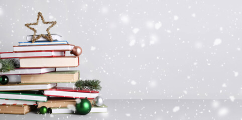 Christmas tree made of different books, balls, fir branches and decorative star on grey background