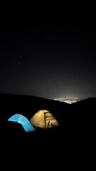 Duas barracas de camping iluminadas à noite em área natural, simbolizando ecoturismo, viagem, aventura e contato com a natureza. © Mari Mont Vibe