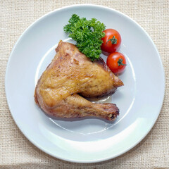 Roasted chicken leg quarter served on a white plate with cherry tomatoes and parsley. Top view rustic food photography ideal for restaurant menus, food blogs, and comfort food concepts.