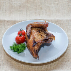 Roasted chicken breast quarter served with cherry tomatoes and parsley on white plate over rustic burlap background. Ideal for recipe blogs, menus, food advertising, and culinary content