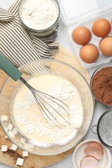Different ingredients for dough and whisk on grey table, flat lay