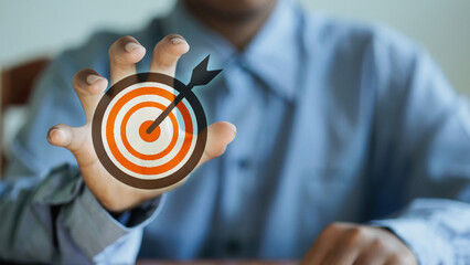Businessman hand reaching to grab virtual dartboard target icon.