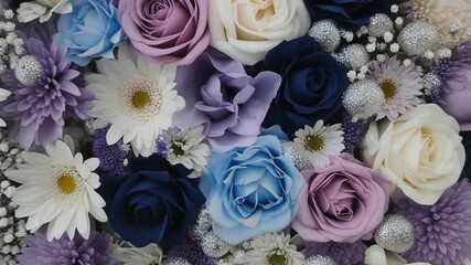 A vibrant close-up of a floral arrangement featuring roses, daisies, and chrysanthemums in various shades of blue, purple, and white, adorned with silver accents