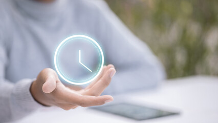 Woman hand holding virtual glowing clock time icon on palm.