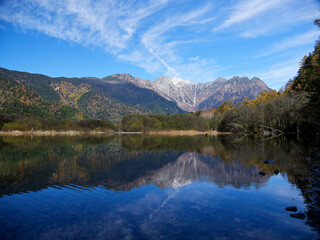 寒い朝の観光名所上高地の大正池と穂高連峰の初雪の風景