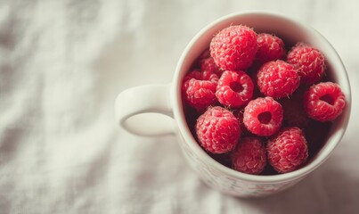 A white cup with a bunch of red raspberries in it