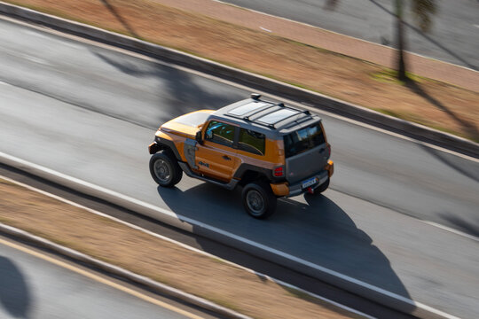 Yellow Troller T4 driving fast on asphalt, Brazilian off-road jeep high angle panning