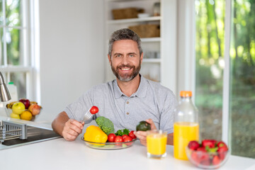 Enjoying healthy food. Man eat morning breakfast in kitchen. Mature man eating lunch. Morning at home. Breakfast in kitchen. Man eating organic vegetable and juice for lunch. Colorful lunch