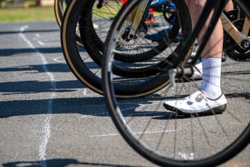 Naklejka premium The starting line of a bicycle race, showing front wheels and feet - horizontal